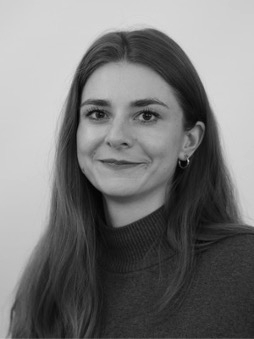 Schwarzweißes Portrait von Sina von Hafe. Weibliche, lächelnde Person mit langen, dunklen Haaren.